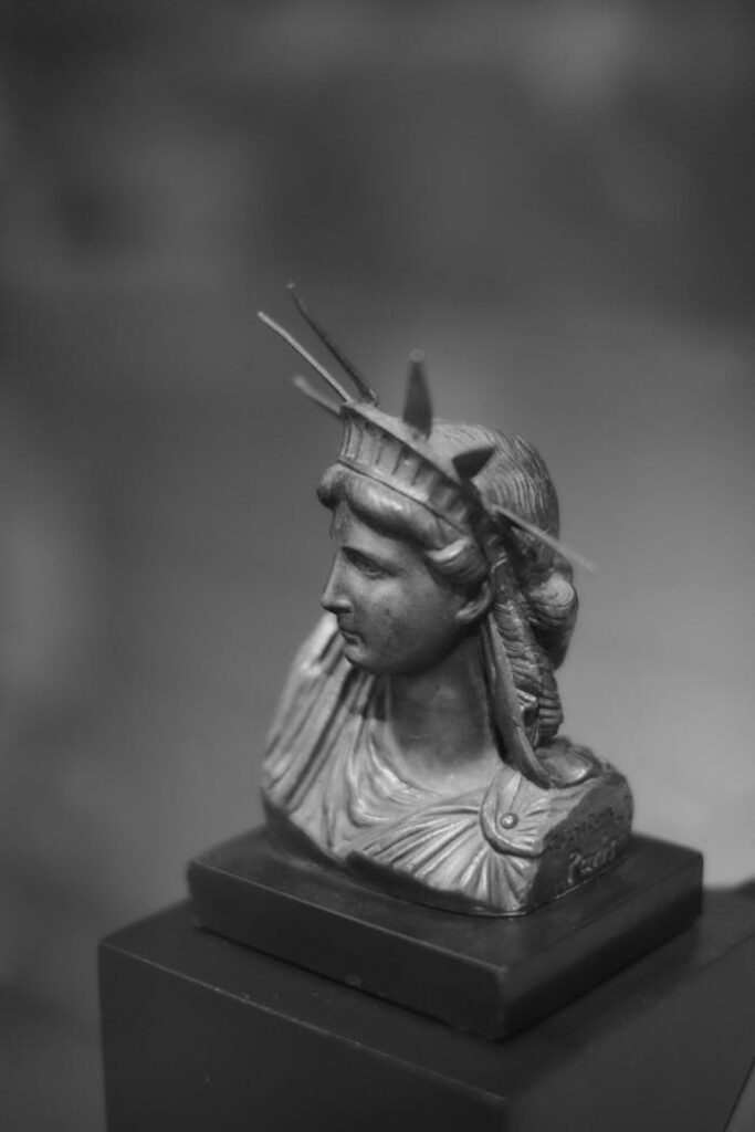Black and white close-up of a miniature bust of the Statue of Liberty, focusing on details.